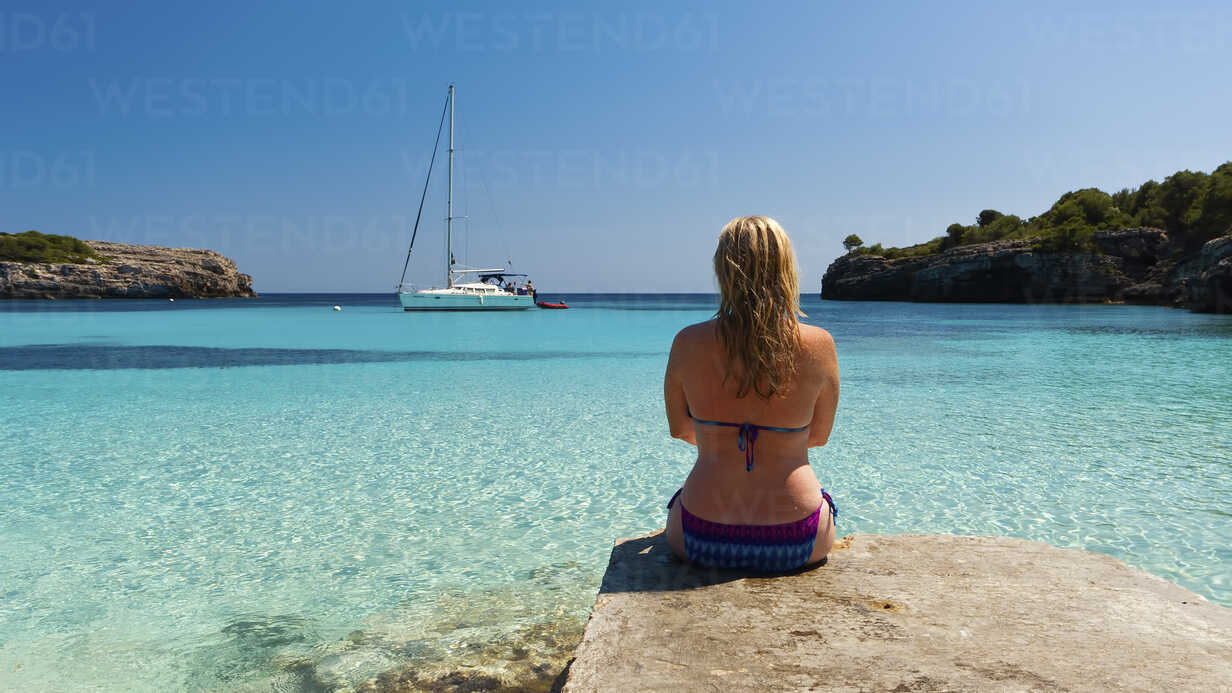 Spain Menorca Woman Sitting On Jetty At Cala Turqueta Smaf Scott Masterton Westend61