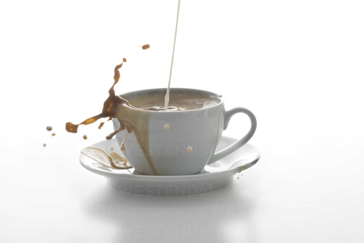 Milk Splashing In A Cup Of Coffee In Front Of White Background Stockphoto