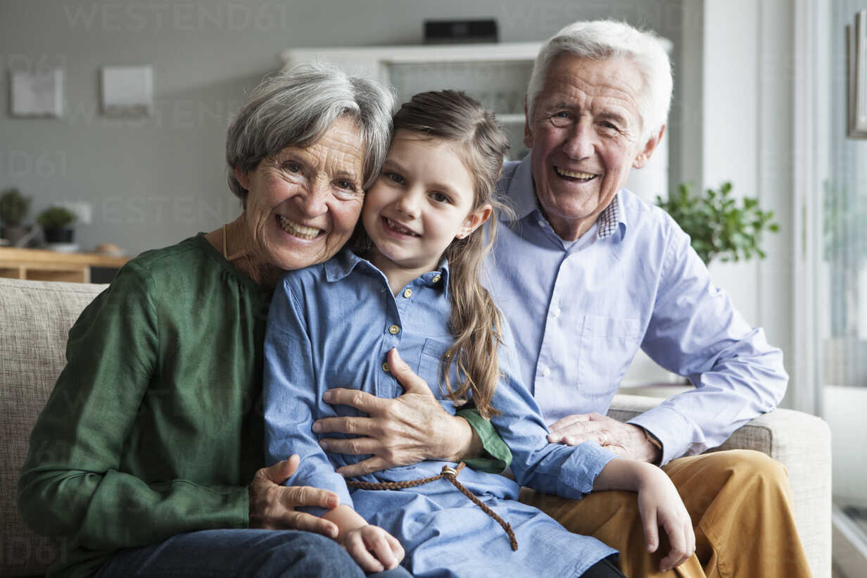 Family Portrait Of Grandparents And Their Granddaughter At Home 