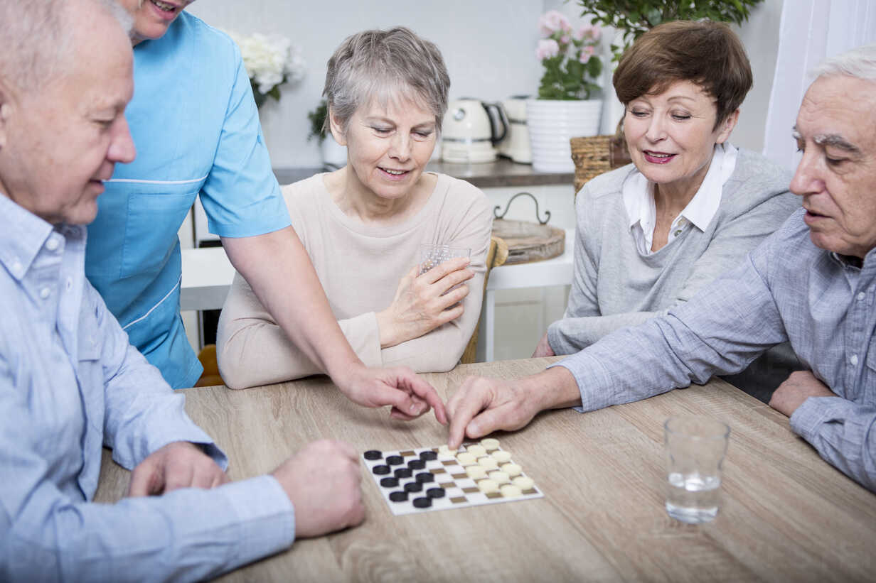 Nurse Helping With A Games Evening For Elderly People Stockphoto