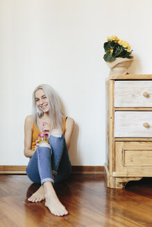 Happy Young Woman Sitting On The Floor At Home Using Smartphone