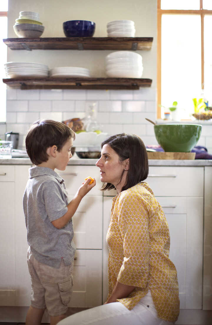 Boy Talking To Mother In Kitchen Stockphoto