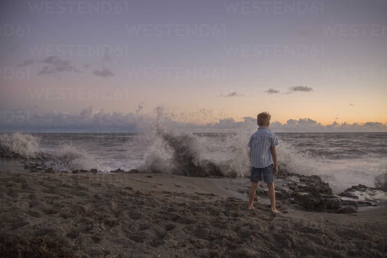 Rear View Of Boy Watching Splashing Waves At Sunrise Blowing Rocks Preserve Jupiter Island Florida Usa