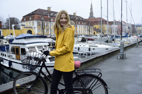 denmark-copenhagen-happy-woman-pushing-bicycle-at-city-harbour-in-rainy-weather-ECPF00652.jpg