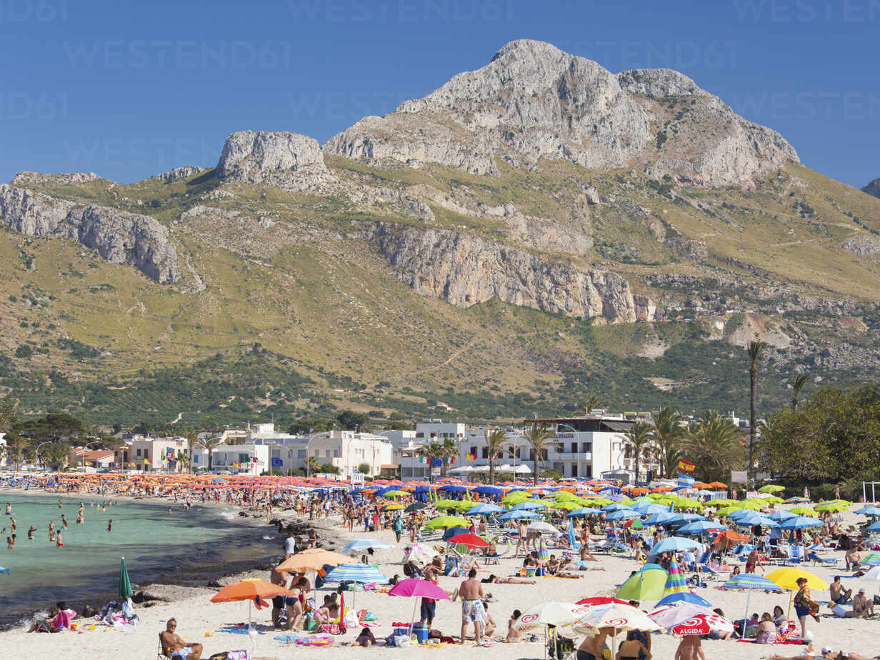 View Across Colourful Crowded Beach To The Rugged Slopes Of Pizzo Di Sella San Vito Lo