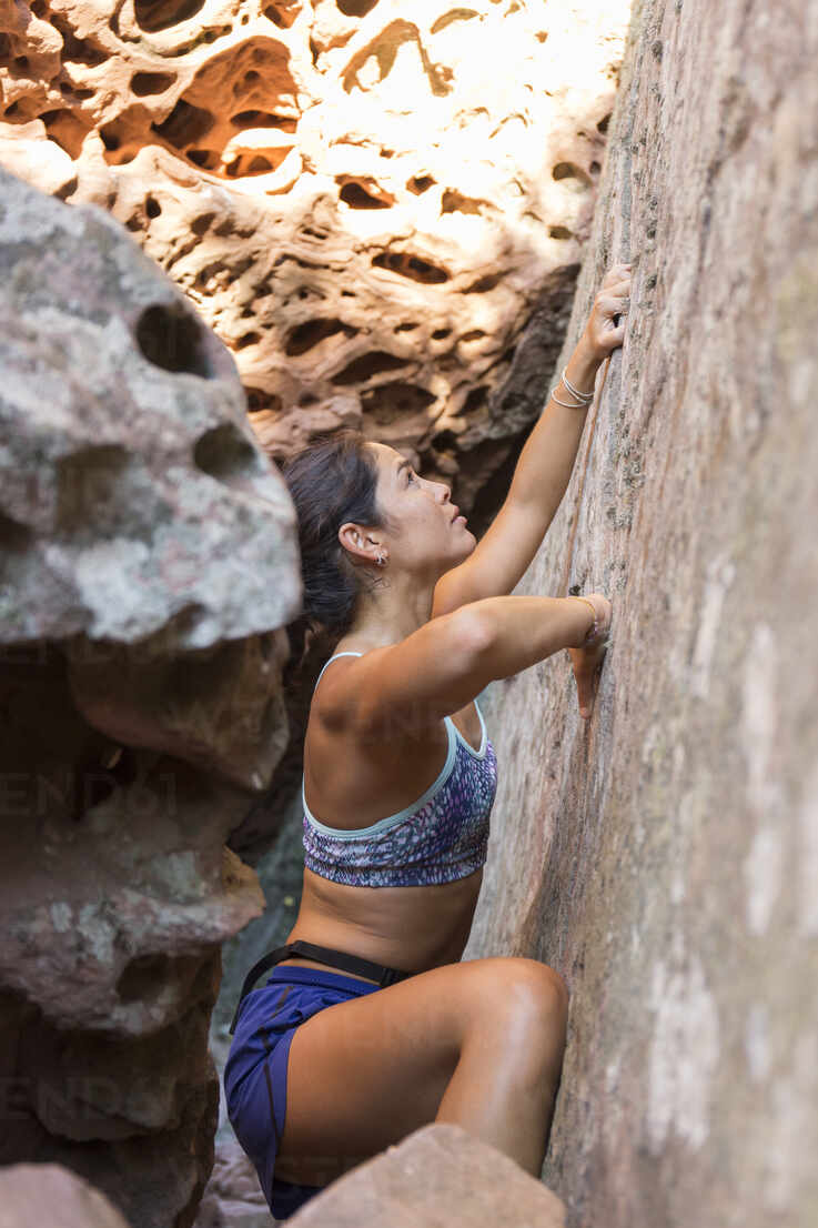 Young Asian Woman Climbing In A Rock Wall Stockphoto