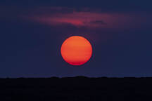 Idyllic Shot Of Orange Moon Over Silhouette Landscape Stockphoto