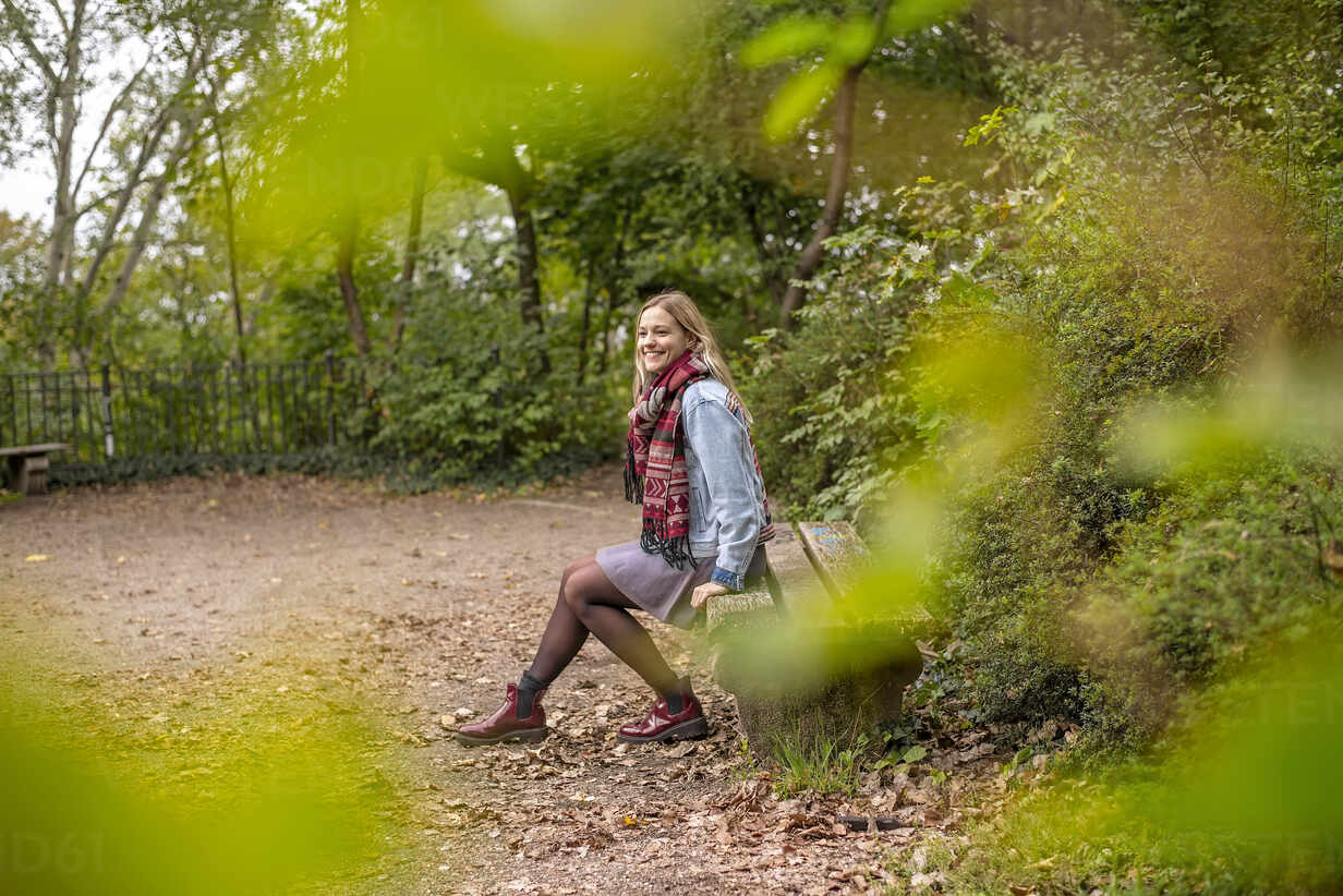 Frohliche Junge Frau Sitzt Auf Einer Bank Im Park Herbst Berlin Deutschland Bfrf Bernd Friedel Westend61