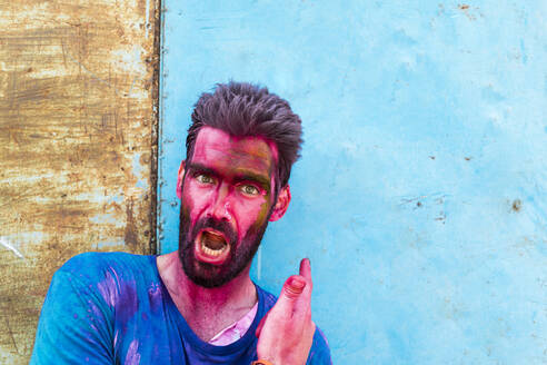 Close Up Of Young Man With Powder Paint Of Face Screaming While Enjoying Holi Festival Stockphoto