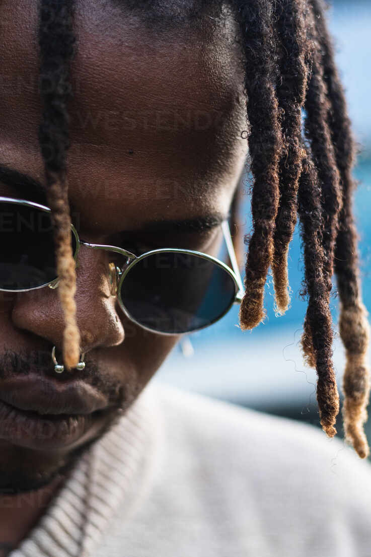 Low Angle Of Modern African American Man In Sunglasses And Dreadlocks In Bun Hairstyle Looking Down