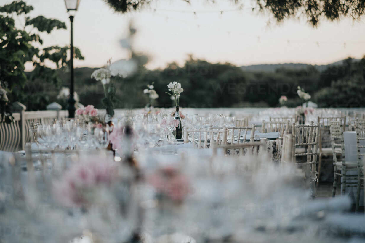 Elegant Tables With Empty Wineglasses And White Flowers During Wedding Ceremony In Garden In Evening Stockphoto